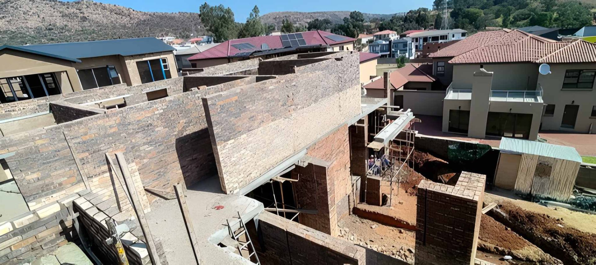 Residential construction site with multiple brick structures and a slab in progress